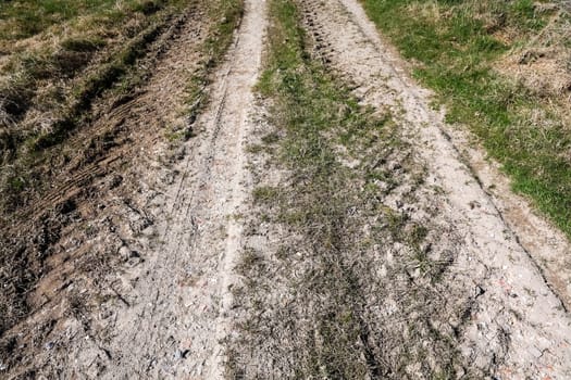 Tire tracks creating a path on a dirt road crossing a field, transportation and off-road concept
