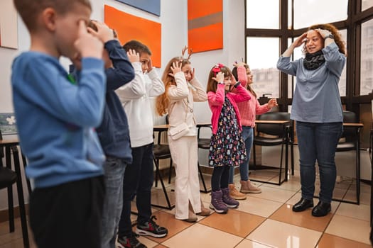 Woman teaching a group of elementary students body parts at language school.