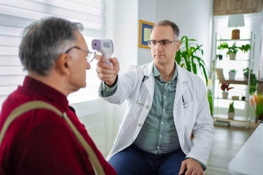 A doctor checks the temperature of an elderly man with a thermometer.