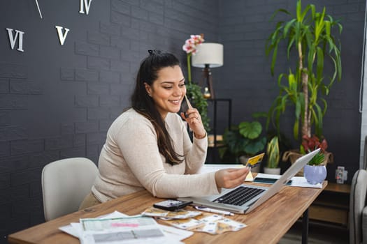 Smiling woman online shopping on laptop at home.