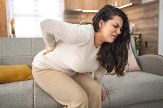 Woman suffering with back pain while at home.