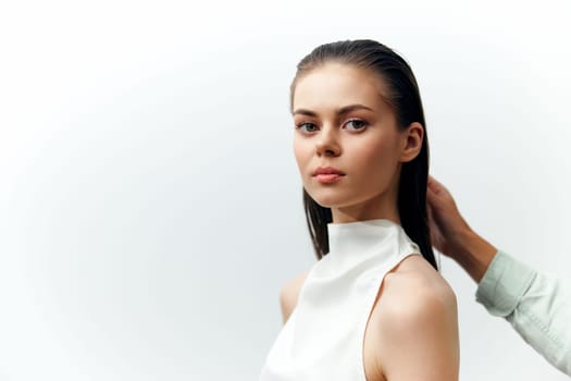 A serene young model exudes elegance with straight hair, wearing a white sleeveless top against a soft, minimalistic background. The focus on the model expression and attire creates a timeless aesthetic.