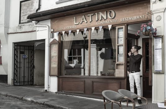 Windsor, UK - Apr 03, 2025 - A restaurant worker taking a cigarette break in front of LATINO continental restaurant. use it as your Wallpaper, Poster and Space for text, Selective focus.