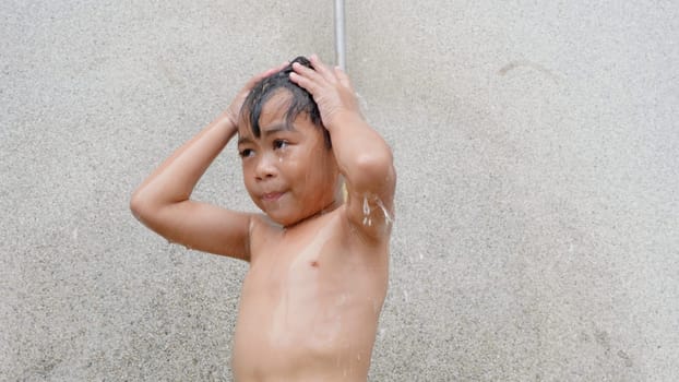 Asian child little boy taking shower at the swimming pool resort, Happy kid after swim he cleaning body refreshing and hyginic in tropical resort during family summer vacation