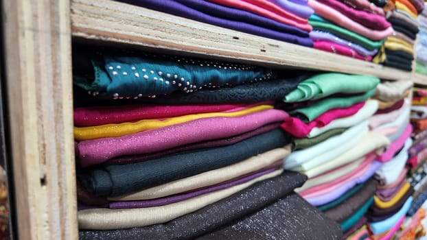 Various vibrant fabric rolls stacked neatly in a textile shop.