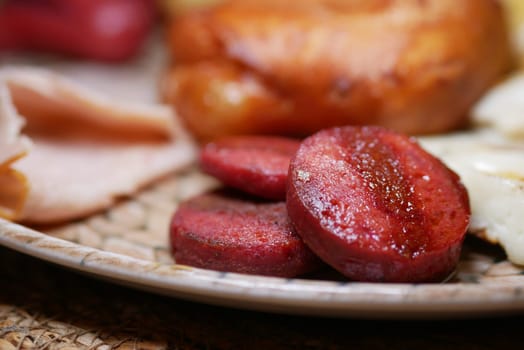 Grilled sausage slices served with bread and eggs on a warm plate.