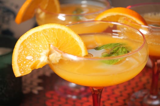 Colorful cocktails are served with orange slices and mint leaves for guests.