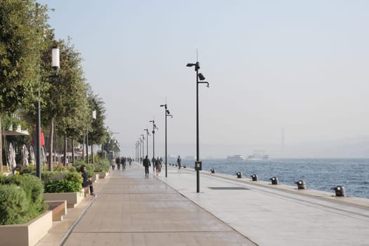 Strollers enjoy a serene morning along the waterfront near the river.