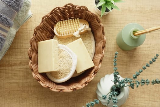 Natural soap bars and a loofah in a basket on a wooden surface with decor.