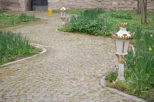 A winding pathway showcases unique lighting and lush plants in spring.
