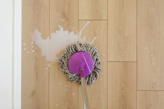 Cleaning a wooden floor with a mop and bucket in a well-lit space.