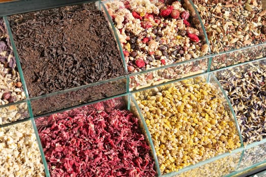 Various dried herbs, spices, and flowers arranged in containers at a market.