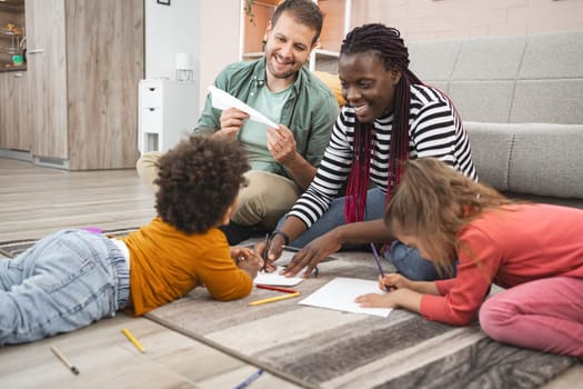 A family spends quality time drawing and coloring on the floor.