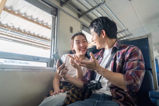 A young couple engages in a lively conversation on a train, capturing a joyful moment filled with laughter. Their connection enhances the travel experience.