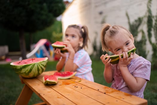 Two cheerful children savor fresh watermelon in a sunlit garden.