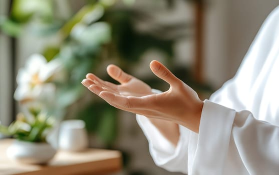 Female hands in peaceful gesture amidst greenery and soft light.