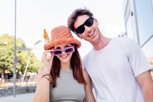 young couple smiling happy looking at camera, the woman is wearing a hat and sunglasses, concept of youth and romance, copyspace for text