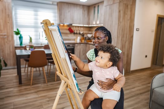 A joyful mother shares a painting moment with her delighted child.