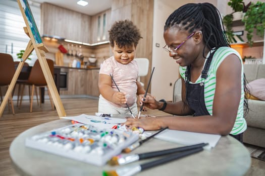 A joyful moment between mother and child as they create art at home.