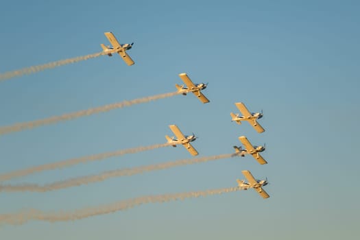 Stunt aerobatic planes performing stunts in blue sky with smoke trail. Concept of teamwork, collaboration, coordination, trust, precision, difficulty, challenge, speed, synergy