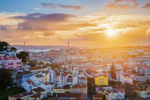 View of Lisbon famous view from Miradouro da Senhora do Monte tourist viewpoint of Carmo Convent Ruins and 25th of April Bridge on sunset. Lisbon, Portugal