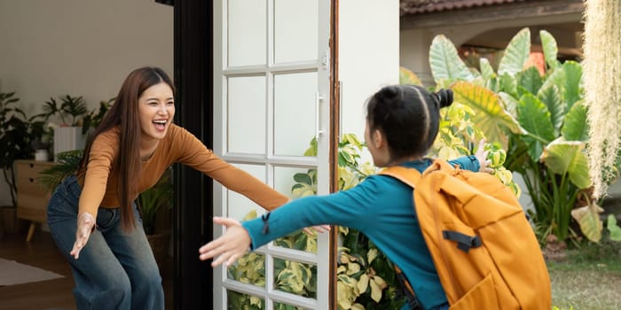The mother smiles and opens her arms to her daughter, expressing excitement and love as she gets ready to leave for school.