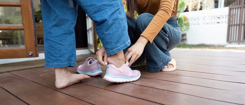 A caring mom assists her daughter with her shoes, emphasizing the nurturing moments before school. Their bond is highlighted in this everyday activity.