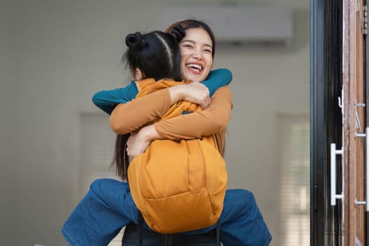 A woman warmly embraces a young girl who carries a backpack, capturing the emotions and excitement of back-to-school readiness and family connection.