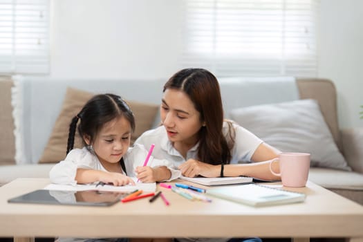The mother and her daughter share a special moment as they engage in writing and drawing, showcasing the importance of parental involvement in early education.