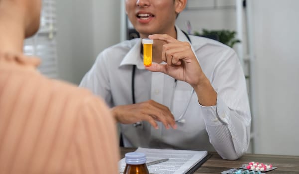 A healthcare professional discusses medication, holding a prescription bottle during a consultation with a patient.