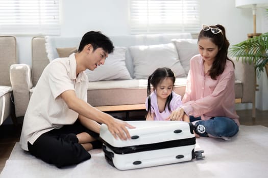 A delightful family scene shows a little girl sitting on a suitcase, engaging her parents with laughter and joy, highlighting the playful aspects of travel planning.