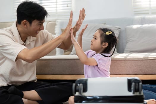 Amidst travel preparations, a father and daughter enjoy quality time together, playfully interacting as they prepare for their trip.