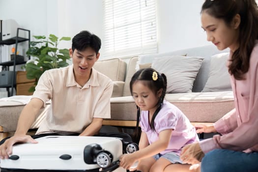 The family shares a light-hearted moment as their daughter plays with a toy suitcase, symbolizing the excitement and anticipation of their travels together.