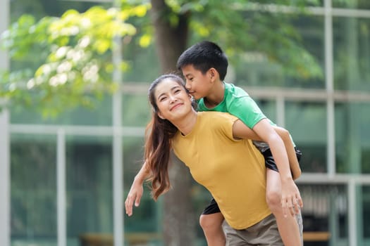 A playful interaction between a mother and her son highlights their close relationship, filled with laughter and joy during a day outdoors.