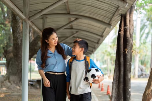 A mother lovingly chats with her son who is excited about soccer, sharing a positive experience on their way to school.