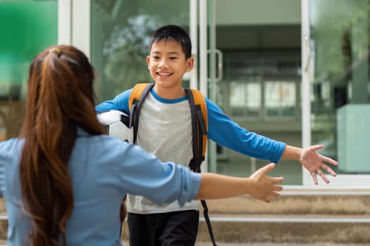 The joy of returning home is palpable as a young boy with a soccer ball excitedly runs into his mother open arms after school.