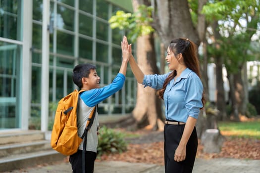 A mother and her son exchange high fives, celebrating the start of another school day together. This image represents joy, encouragement, and the importance of family support in education.