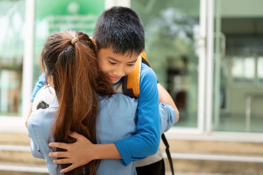 A touching moment unfolds as a young boy with a soccer ball is enveloped in a warm hug from his mother at the school's entrance, celebrating their bond.