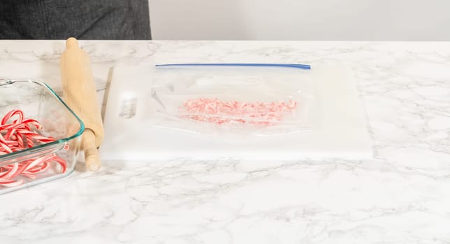 Castle Rock, Colorado, USA-November 26, 2024-Focused view of a rolling pin placed next to a ziplock bag filled with partially crushed candy canes, set on a marble surface for baking preparation