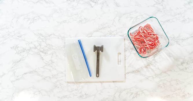 Castle Rock, Colorado, USA-November 26, 2024-Tools for crushing candy canes displayed on a marble surface, including a small mallet, plastic bag with crushed candy, and candy canes in a container