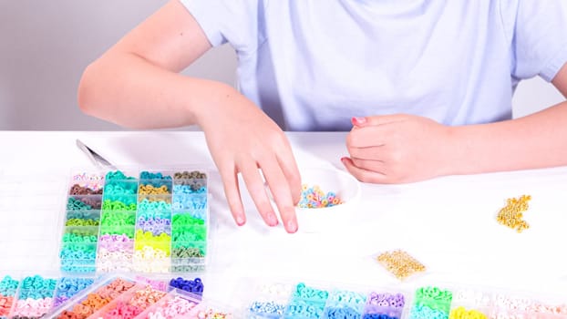 Delicate fingers of a young girl navigate through a treasure trove of bright, multicolored beads, each compartment revealing a new hue to choose from.