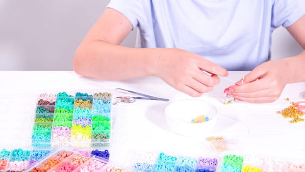 Delicate fingers of a young girl navigate through a treasure trove of bright, multicolored beads, each compartment revealing a new hue to choose from.