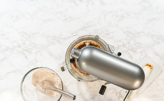 Overhead view of a mixing setup with flour, spices, and a stand mixer for Spiced Gingerbread Cookie Dough Perfect for Baking. Bowls of dry and wet ingredients are ready for blending.