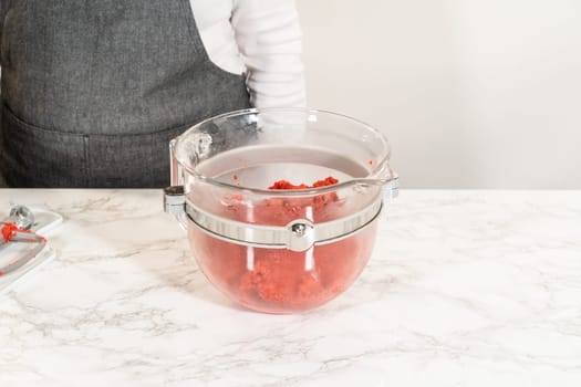 The Classic Red Gingerbread Dough taking shape in the mixing bowl as the ingredients come together. This red-hued dough will soon be ready for chilling.