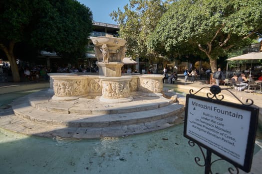 Crete.Greece - april 07, 2025: Renaissance architecture meets daily life at the Morosini fountain, where tourists and locals gather around its ornate details in the lively plaza of Heraklion.