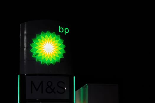 London, United Kingdom - February 01, 2019: Green and Yellow bp sun sign glowing in night on one of their petrol station at Lewisham. British Petroleum is oil, gas, energy company founded 1909