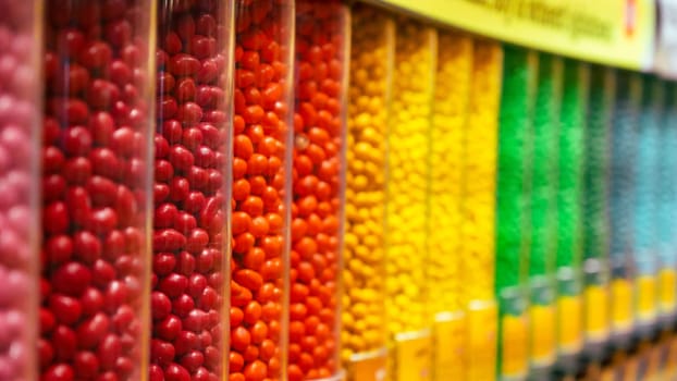 Colorful round candies displayed in clear plastic containers, arranged in a neat row. Perfect for backgrounds or illustrations related to the confectionery industry.