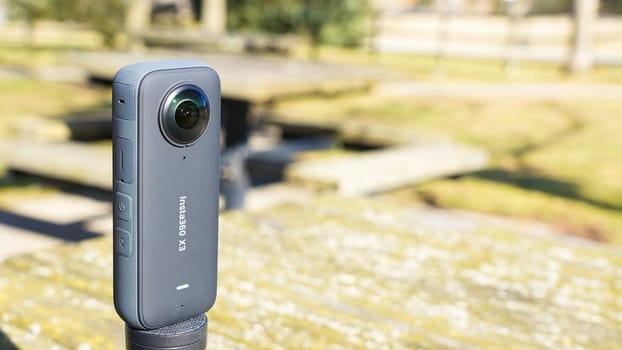 Syracuse NY USA - 08.02.2024: Black Tripod with Insta360 Camera Positioned on a Table in a Scenic Outdoor Park Setting.