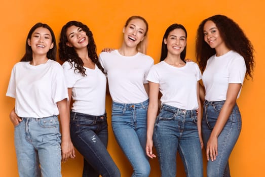 Five Cheerful Young Ladies Smiling To Camera Posing Together Standing On Yellow Background, Studio Shot, Wearing Casual Clothes. Multicultural Female Friendship And Diversity Of Beauty