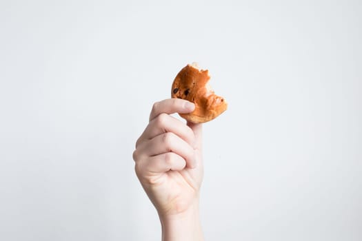 Hand holding chocolate chip cookie bite against white background.